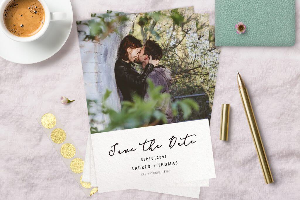 Affectionate Couple's Photograph on Save the Date Card, Set on White Surface with Golden Pencil and Coffee Cup.