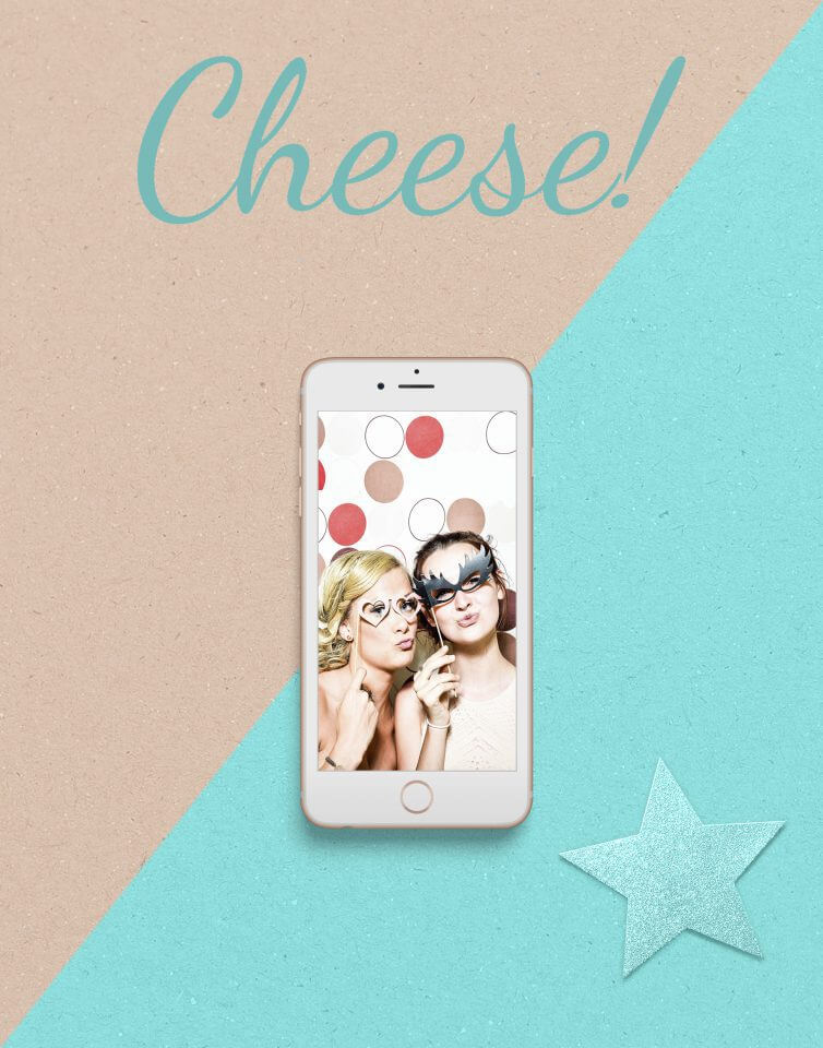 A camera phone captures a cheerful moment with girls smiling for a photo, the smartphone placed on a surface adorned with a sparkly blue star and the playful prompt 'Cheese!