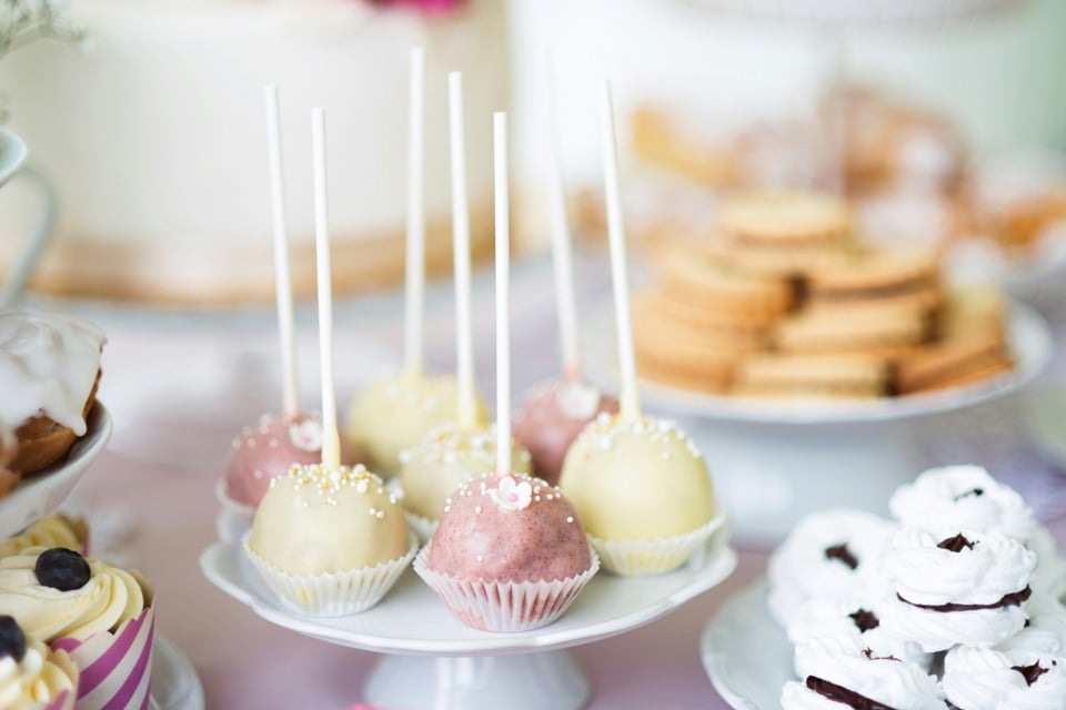 sleepover-party-snacks-sweets Assorted sleepover party sweets arranged on pastel stands, featuring cake pops with sprinkles, frosted cupcakes, and stacked cookies, creating a soft, cozy dessert table for a girls’ sleepover celebration.