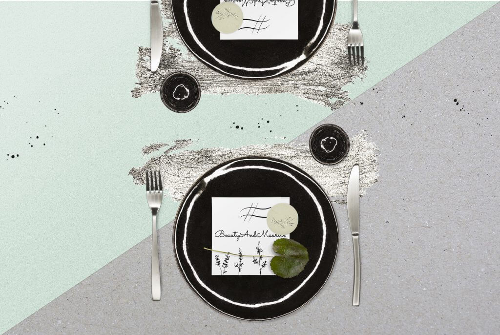 Wedding Dinner Setting: Black Plates, Silver Utensils, and Name Cards Resting on Top.