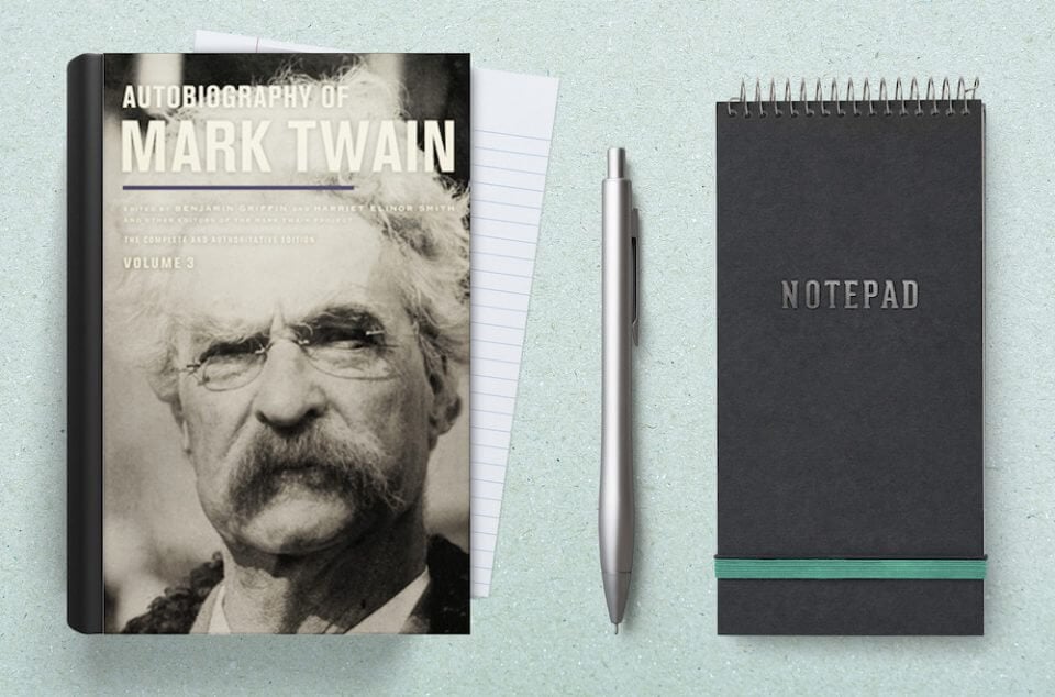 A copy of Mark Twain's autobiography placed next to an open notebook. This arrangement suggests a space for taking notes or reflecting on the content of the book.