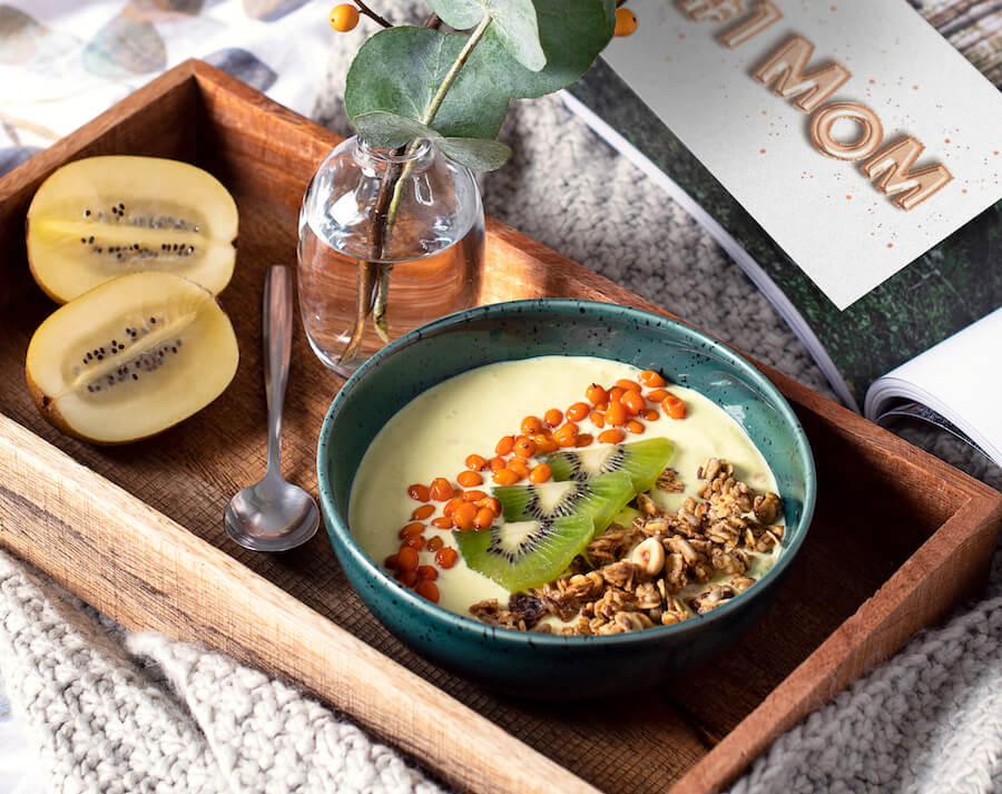 A Mother's Day breakfast in bed setup, likely representing one of the '20 Mother’s Day Ideas to Show Mom You Care'. The image features a breakfast tray with a card for mom, symbolizing a thoughtful and pampering gesture to celebrate Mother's Day."