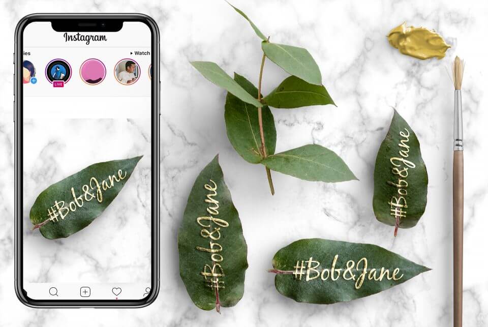 Capturing Wedding Hashtags: Expert Tips for Perfect Wedding Invitations Design. iPhone Photo: Gold-Embossed Leaf with Bride and Groom's Names. Elegant Marble Backdrop.