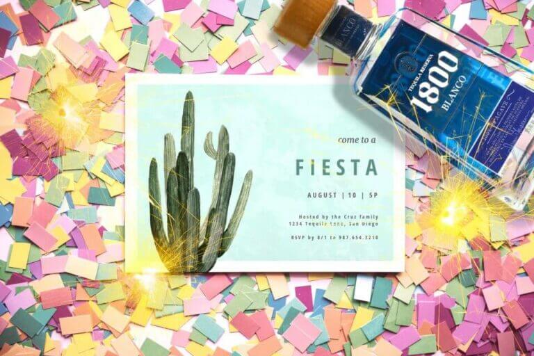 Fiesta invitation featuring a charming cactus design, placed atop a bed of colorful confetti and positioned near a festive bottle of drink