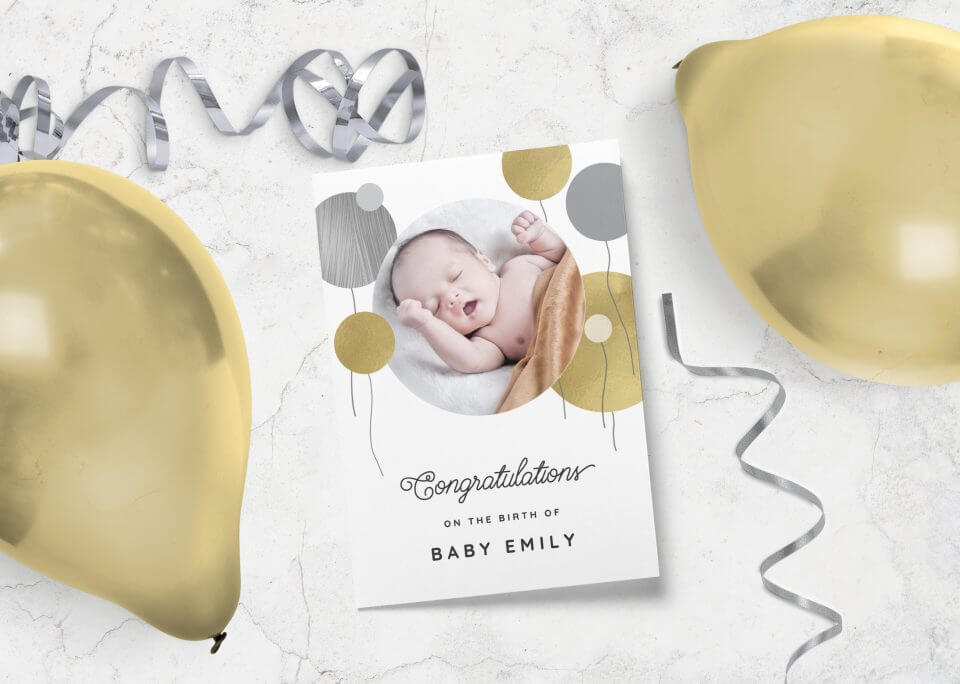 New Baby Balloons Card featuring a central balloon illustration with an adorable baby photograph. Positioned near a cluster of golden balloons for added celebration.