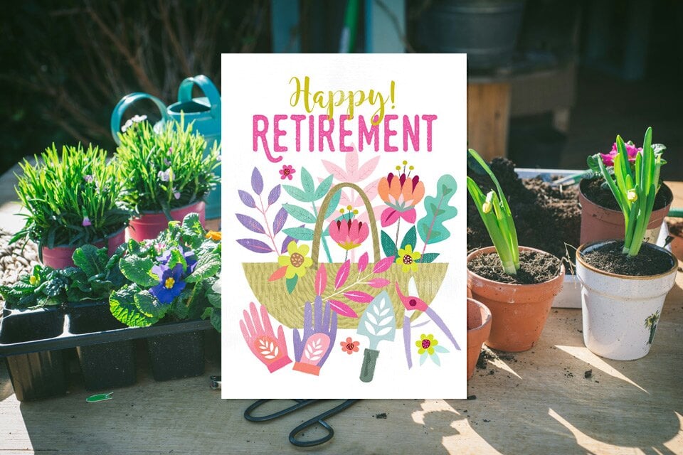 1 happy-retirement-gardening-flowers-card Colorful happy retirement card with gardening flowers and tools displayed beside potted plants in sunny garden workspace.