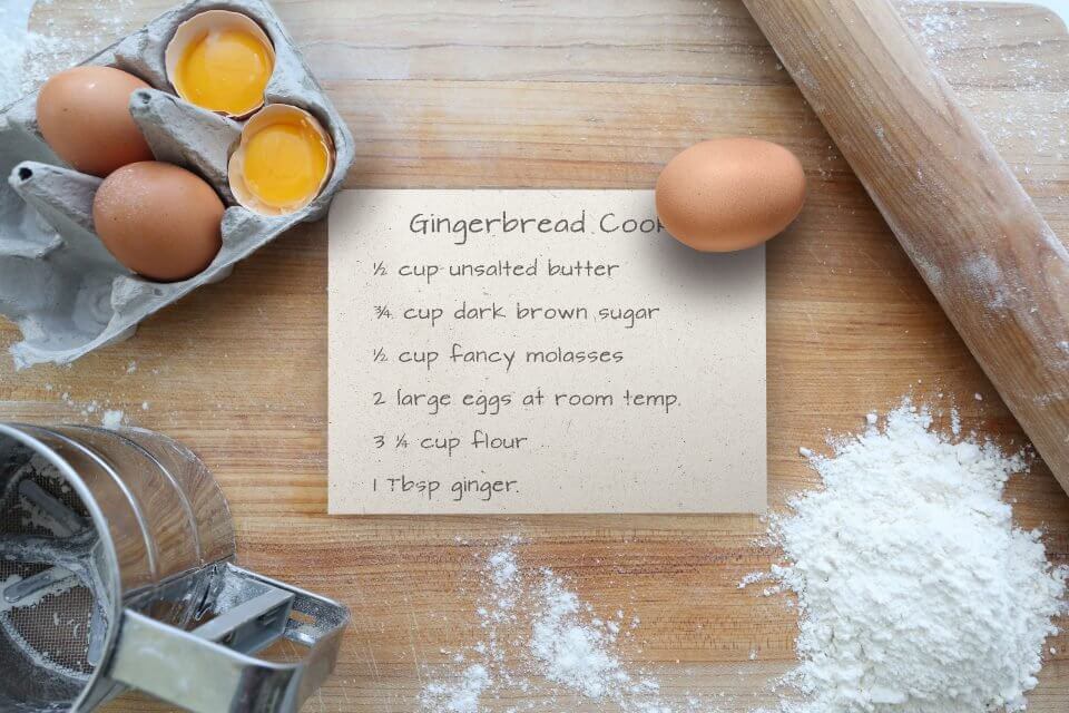 Scrumptious Gingerbread Cookies Recipe: Handwritten on a piece of paper placed on a Floured Tabletop, Alongside Flour, Sugar, Eggs, and a Rolling Pin Ready for Baking