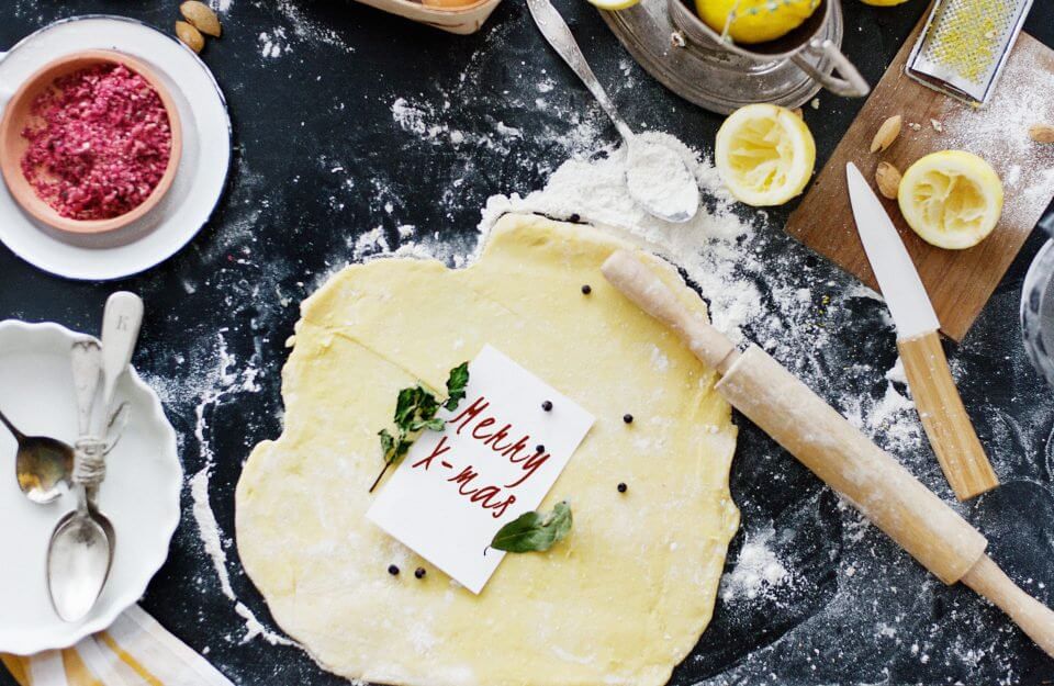 Festive Christmas Baking Scene: Cookie Dough Rolled Out with a Cheery 'Merry X-Mas' Note, Alongside Flour for Kneading, a Rolling Pin, Knife, Fresh Lemon, and Minced Meat Ready for Holiday Delights