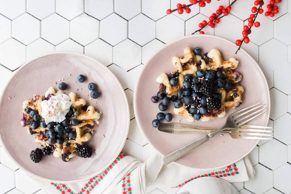 Delightful Christmas Waffles Adorned with Juicy Blueberries, Presented on Elegant Light Pink Plates