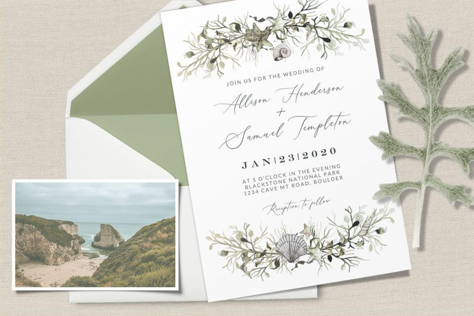 Marine Nautical Wedding Invite: Seashells and marine plants border, elegant centered text. Rests on light cream background with envelope and beach photograph.