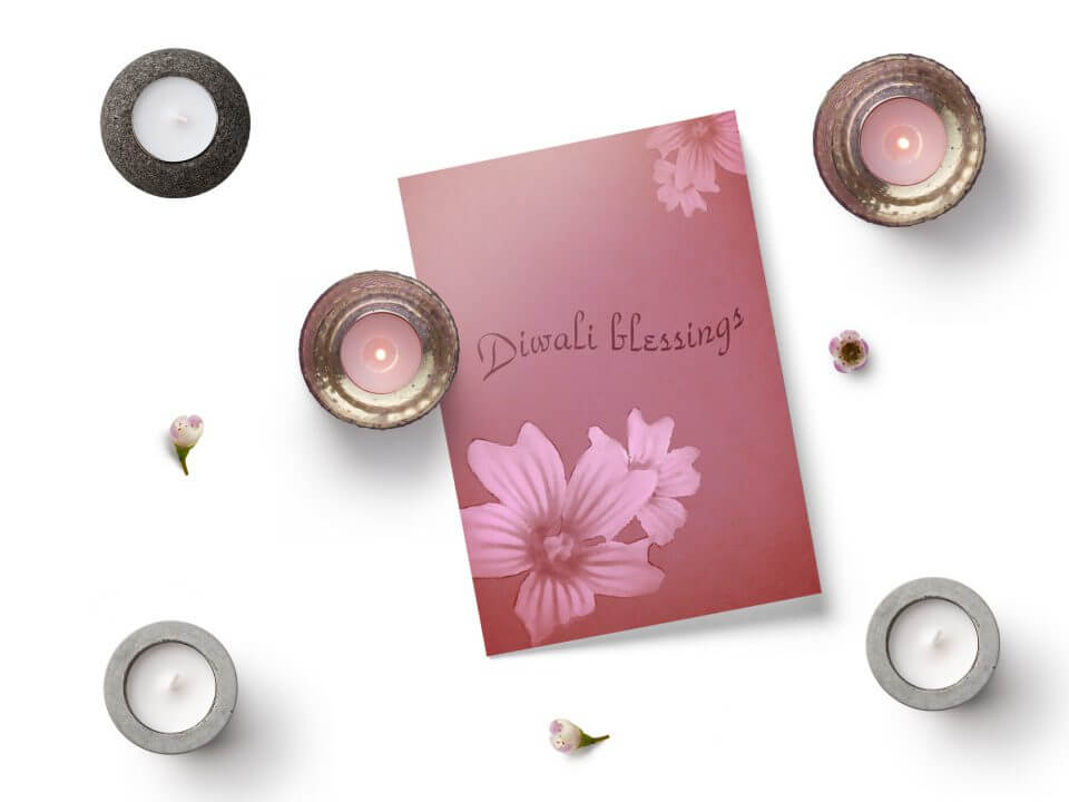 Sharing Diwali blessings through a gracefully designed card adorned with intricate flowers, radiating simplicity and beauty. The card is thoughtfully placed next to flickering lit candles