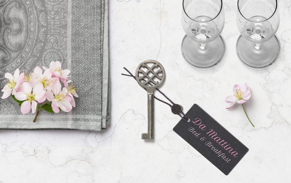 A romantic scene set in a hotel room, featuring a hotel key resting on a sleek surface, accompanied by two glasses of champagne and a bouquet of flowers.