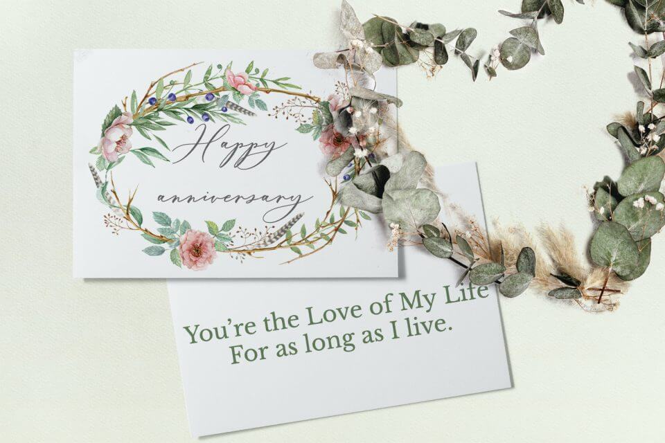 Extend warm wishes for a Happy Anniversary with an elegant card adorned with a wreath of leaves and flowers, exuding timeless charm and celebration.