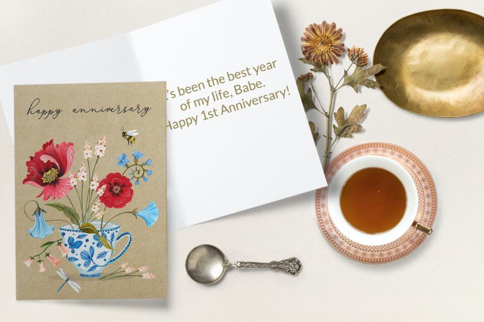 Send heartfelt wishes for a Happy Anniversary with an exquisite card adorned in brown paper flowers and a charming teacup illustration, creating a warm and inviting sentiment.