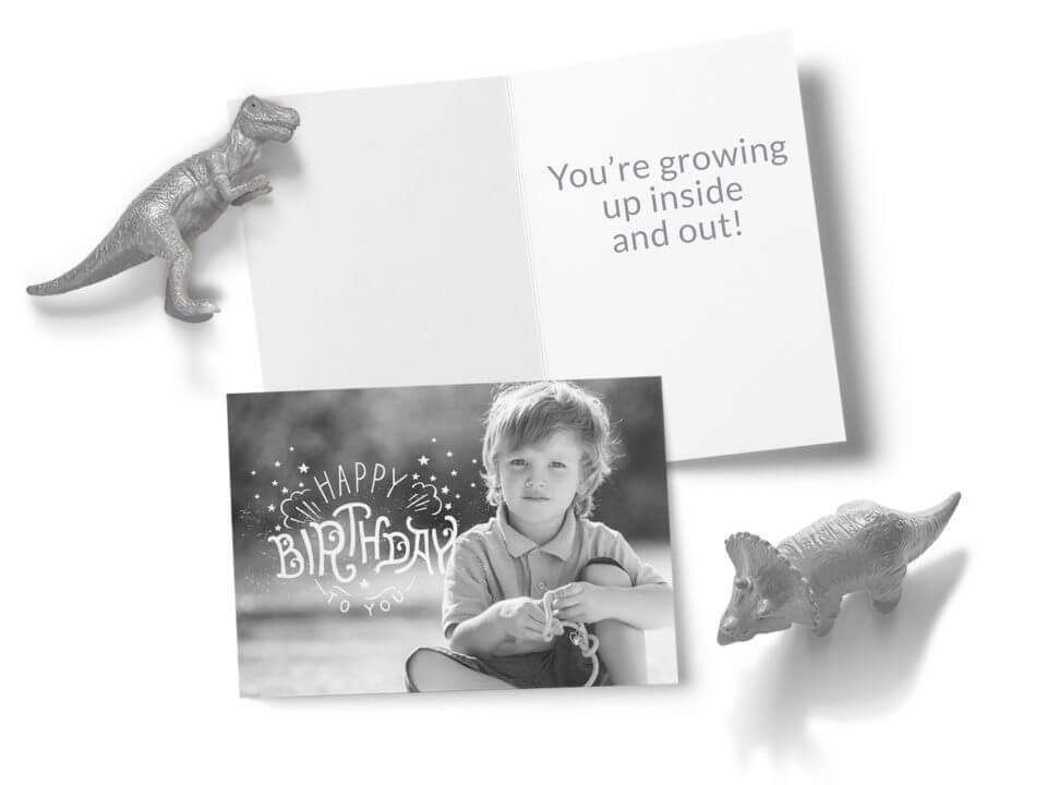 Timeless Birthday Wishes & Greetings for All. A Classic Black and White Photography Card with 'Happy Birthday to You' on Top. Displayed on a Surface with Two Playful Dinosaur Toys Nearby, Alongside an Open Card.