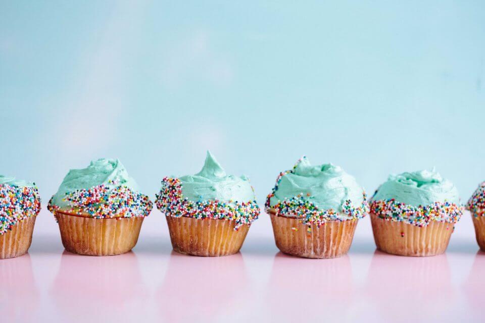 Six light green cupcakes adorned with a burst of vibrant sprinkles, ready for a fun-filled girls' birthday party.