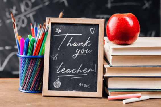 Thank you teacher handwritten note on chalkboard with stack of books.