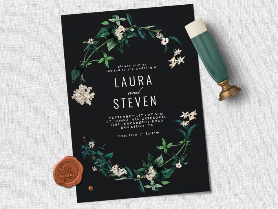 Hydrangea Wedding Invite: Elegant black background, floral illustration, white text. Rests on a light grey surface with a vintage stamp nearby.