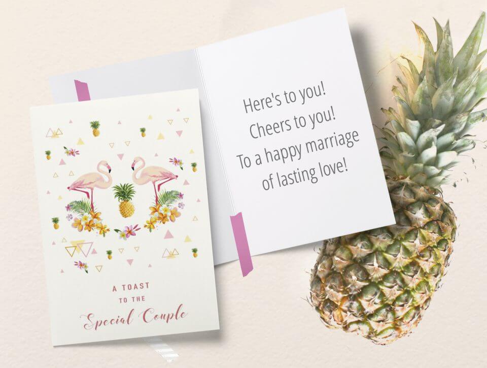 Flamingo-themed wedding card: Two facing flamingos, pineapple centerpiece, floral backdrop. Red text: 'A toast to the special couple.' Open card reveals a meaningful quote. Pineapple accents complete the scene.