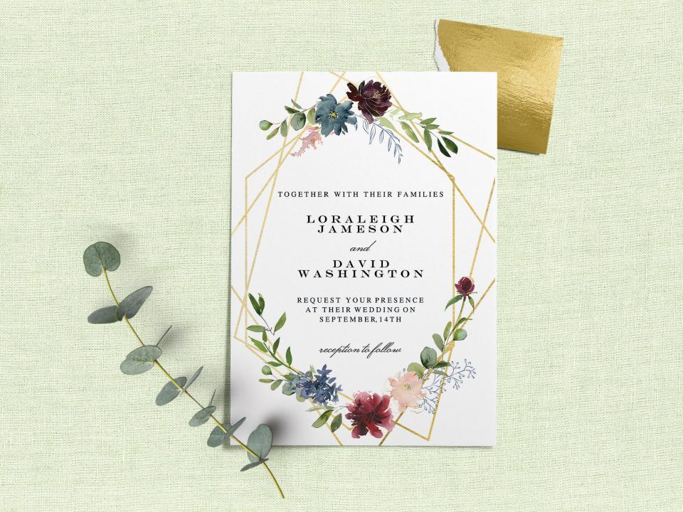 Geometric & Flowers Wedding Invite: Gold border with stunning flower illustrations. Elegant black text. Rests on light green surface with a verdant branch on top.