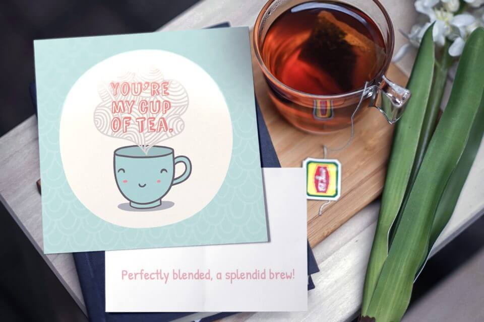 You're My Cup of Tea: Illustrated Teacup Steaming with a Cheerful Smiley Face, Teal in Color. White Text with Orange Drop Shadow. Set Against a Background of Tea Cups and Blooming Flowers.