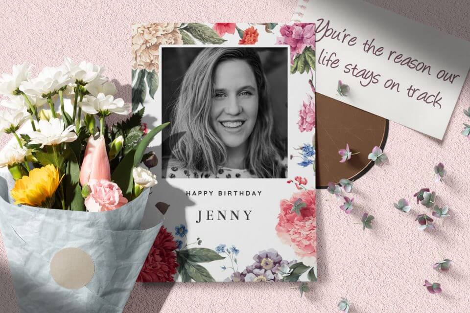 Vintage Floral Birthday Card: Colorful Blooms Frame a Cherished Photo, 'Happy Birthday Jenny.' Resting on a Pink Surface, Adorned with a Bouquet of Fresh Flowers.