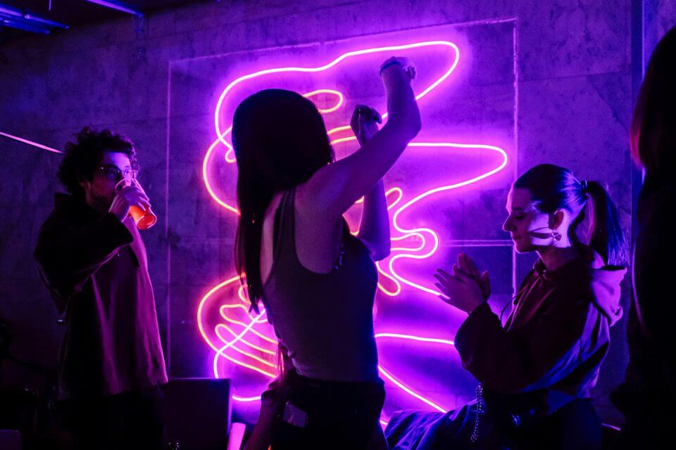 Captivating image of a dynamic nightclub scene at night, with energetic people dancing amidst neon lights, creating a vibrant and unforgettable party atmosphere.