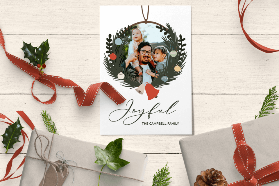 Enchanting Christmas Card: Happy Family in a Wreath of Evergreen Branches, Red Berries, and Gold Bows on a Wooden Table, Adorned with Wrapped Gifts - cover for "10 Christmas Decor Ideas to Wow Your Guests"