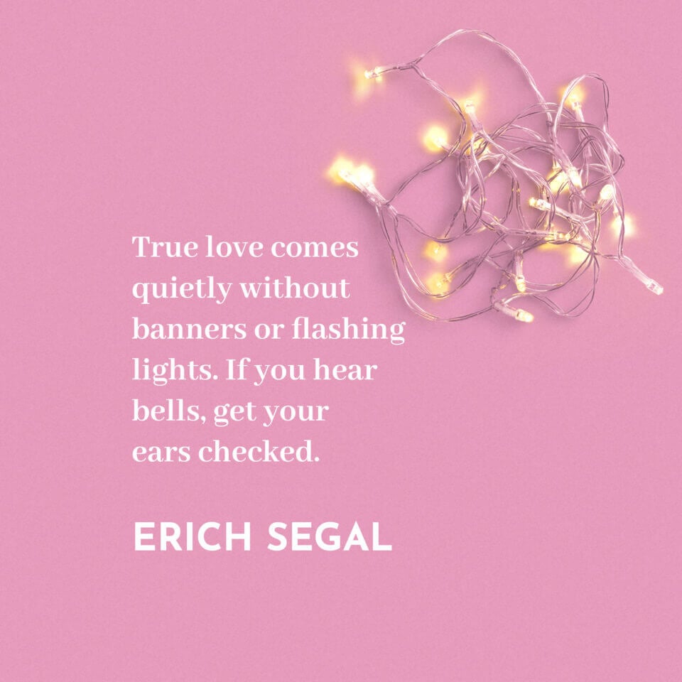 Quote by Erich Segal: 'True love comes quietly without banners or flashing lights. If you hear bells, get your ears checked.' Against a pink background, adorned with delicate string lights.