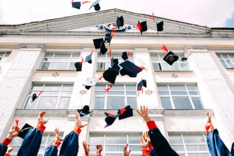 An image depicting 'IDEAS INSPIRATION 30 Graduation Announcement Wording and Messages for High School and College Graduation', featuring a group of students in the celebratory act of throwing their graduation caps into the air.