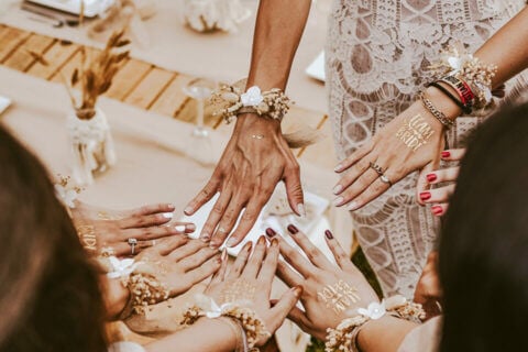 Diverse women with 'TEAM BRIDE' & 'BRIDE' tattoos form a joyful circle, radiating unity. cover for '7 Fun Bridal Shower Ideas' blog post.