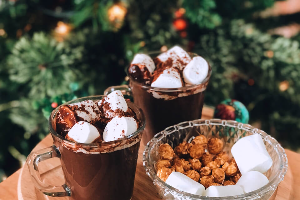Indulgent Hot Chocolates: A Delightful Treat at a Winter Holiday Christmas Wedding, Served in Glasses Against a Festive Christmas Tree Backdrop