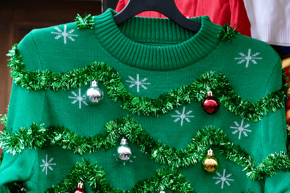 Festively decorated ugly green Christmas sweater adorned with an array of colorful Christmas ornaments.