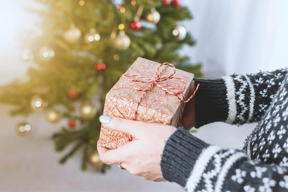 Sharing the Holiday Spirit: Hands in Festive Sweater Exchanging Christmas Gifts