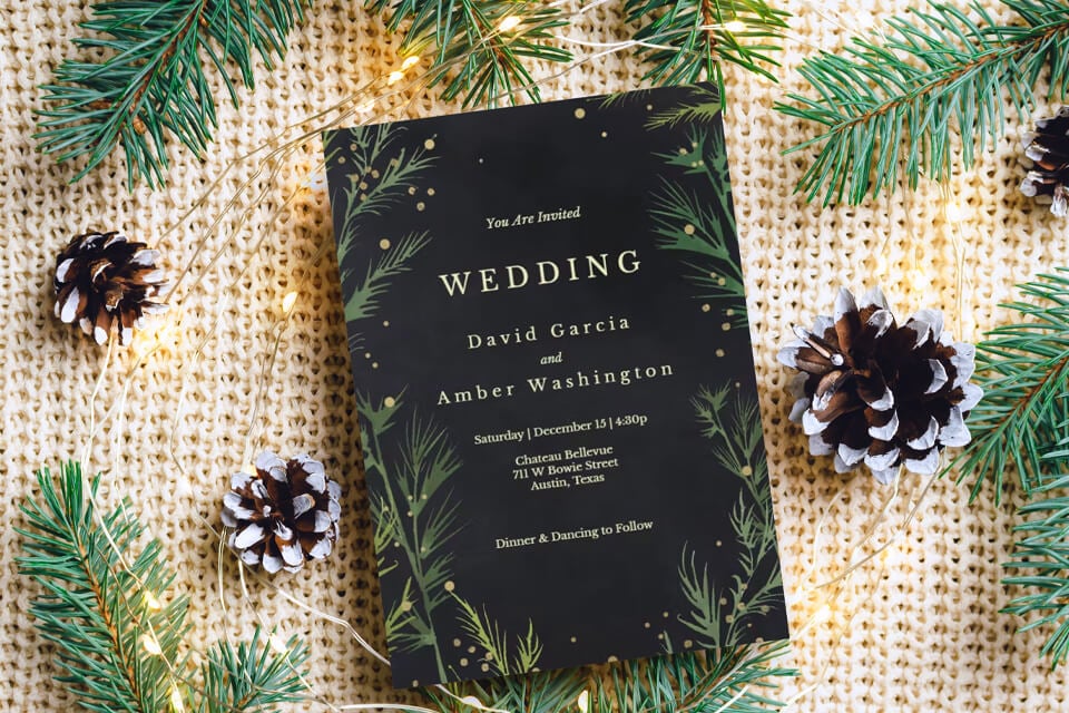 Exquisite wedding invitation card featuring illustrated pine tree branches with golden sparkles on a black background. Garland lights and additional pine tree branches complement the inviting design against a knitted backdrop.