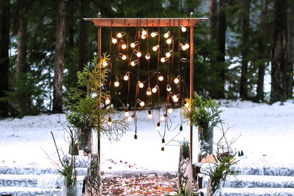 Winter Wedding Arch adorned with Festive Lights and Garland in a Snowy Outdoor Setting.