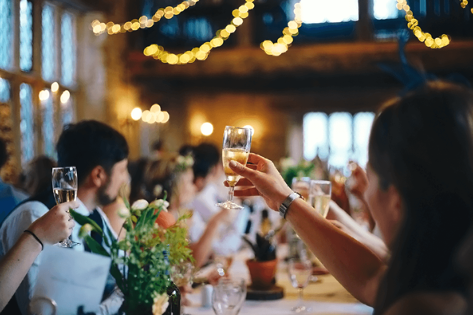 Joyful guests raising champagne glasses in a celebratory toast at a beautifully set engagement party table