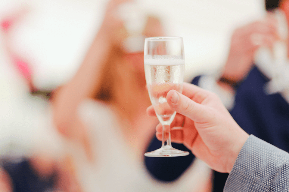 hand holding a champagne glass at a Wedding Rehearsal Dinner making a toast