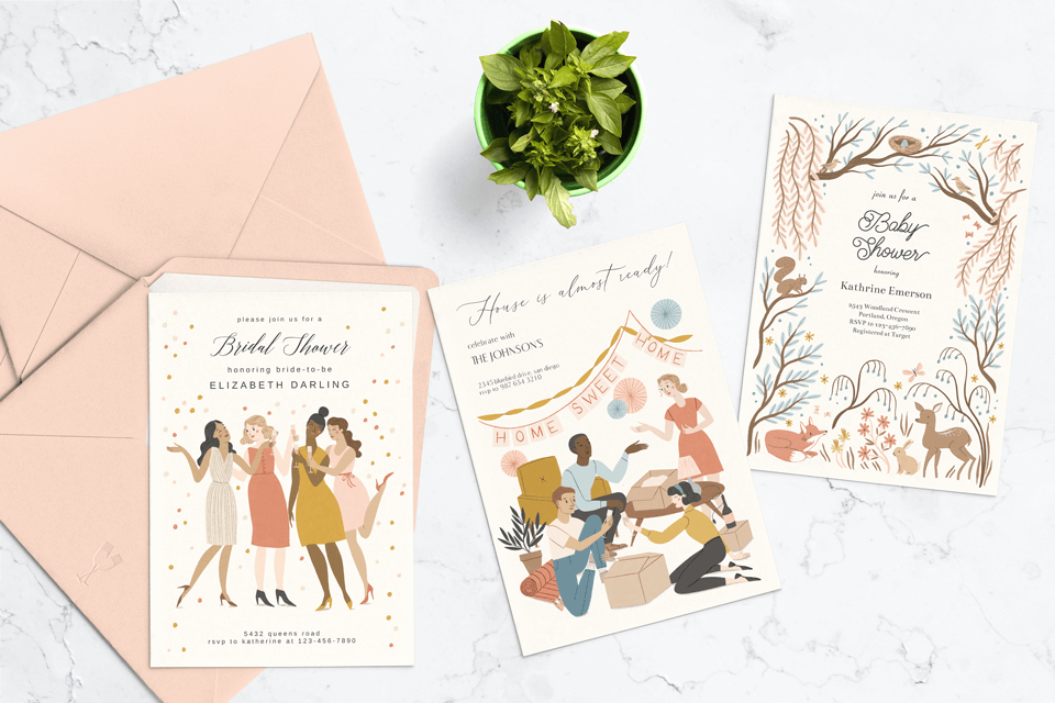 A set of Meghann Rader' invitation designs for Greetings Island, displayed on marble with pink envelopes and a flower pot. The collection includes a bridal shower invitation with a cheering woman, a housewarming invite showing people unpacking, and a baby shower card with forest animals."