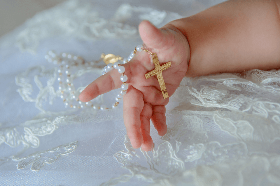 baby holding a cross in their hand
