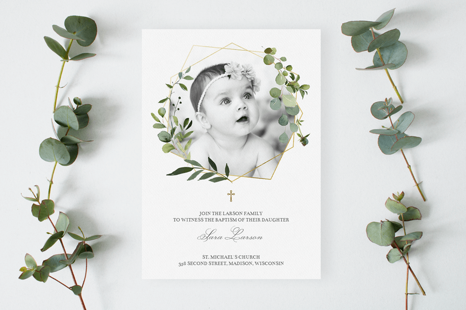 geometric and greenery baptism and christening invitation sitting on a table with eucalyptus branches close by