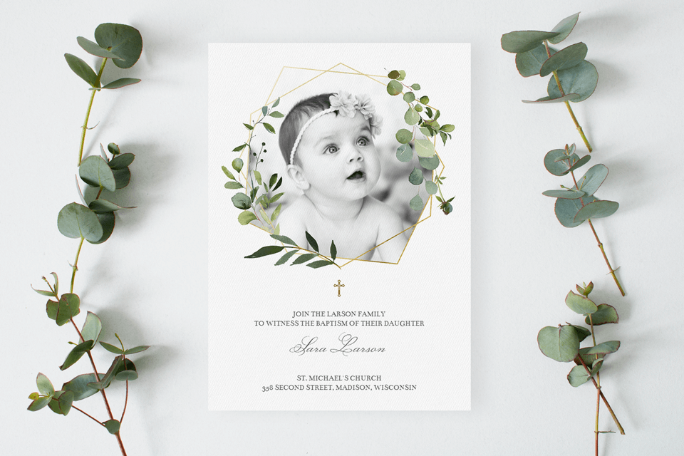 A geometric and greenery-themed baptism and christening invitation displayed on a table, with the fresh, aromatic presence of eucalyptus branches nearby, complementing the invitation's natural elegance.