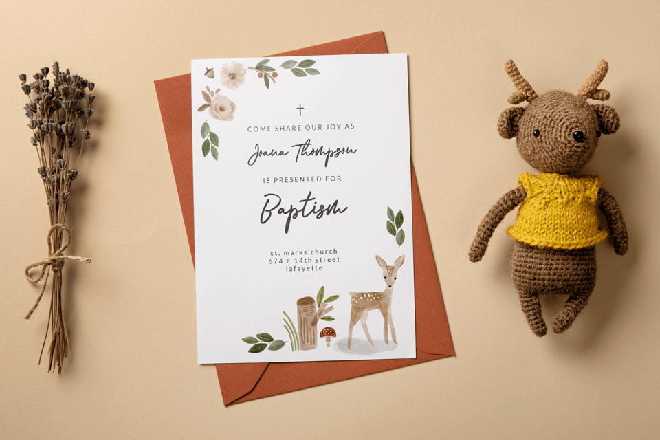 Animal-themed baptism and christening invitation resting on a table beside a charming crocheted deer and a spray of flowers, setting a whimsical tone for the sacred occasion.