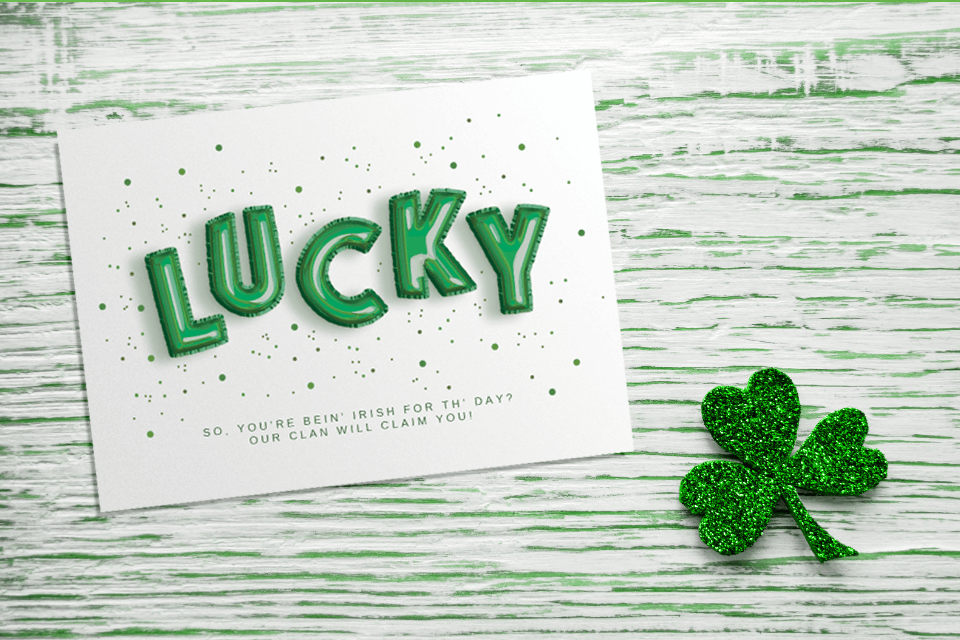 Lucky greeting card for St. Patrick's Day sitting on a wooden surface with a lucky clover close by