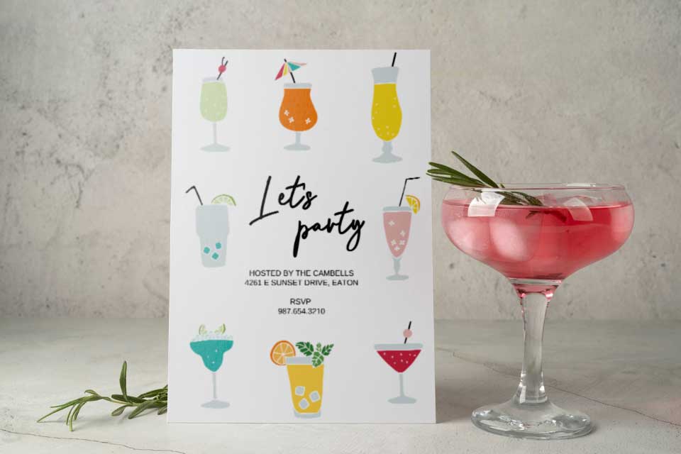 a cocktail glass standing next to a cocktail party invitation