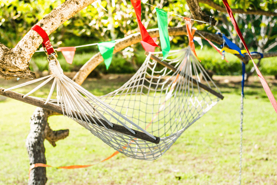 A hammock captured in an outdoor setting at a graduation party, symbolizing relaxation and celebration. The hammock is strung between two trees, set against a backdrop of a festive party atmosphere, reflecting the joy and leisure of the occasion