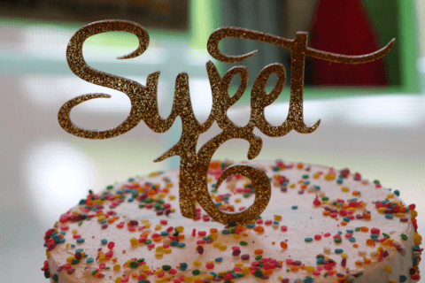 Close-up of a golden 'Sweet 16' cake topper adorning a vibrant cake with a sprinkle-covered decoration. Cover for the blog post: 'A Complete Baby Shower Planning Checklist for a Memorable Celebration'
