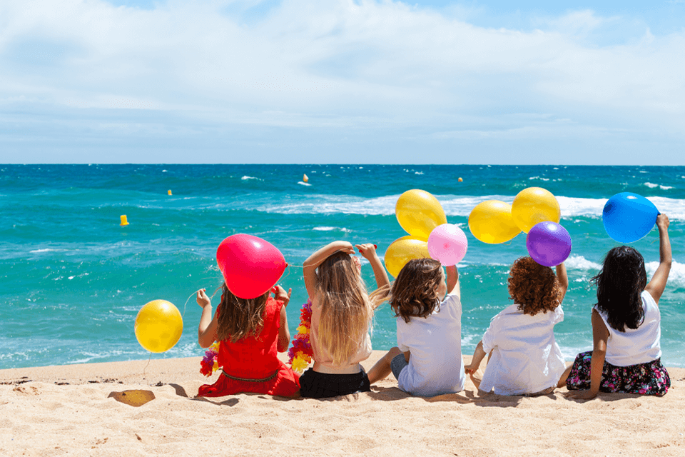 Vibrant Beach Birthday Celebration: Five Kids with Colorful Balloons Enjoying the Shoreline
