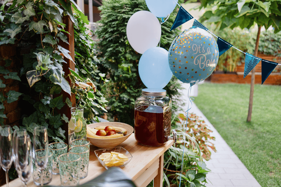 Baby shower table setting with balloons, fruit, and juice.