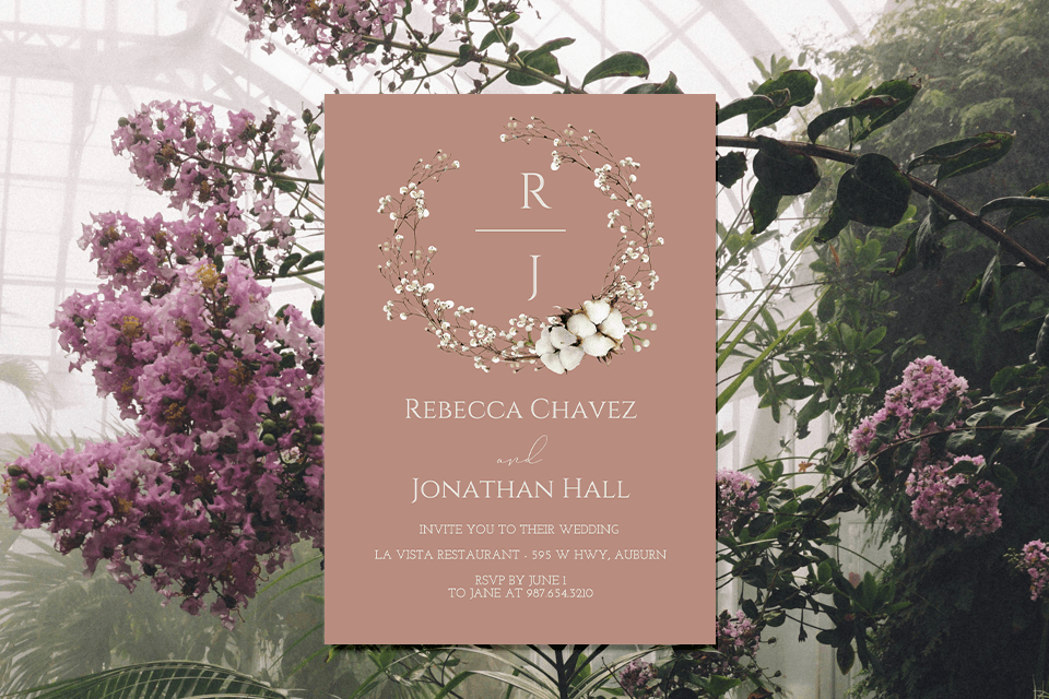 An exquisite wedding invitation featuring a delicate wreath of white flowers illustrated on a soft peach-colored background. The invitation is presented against a backdrop of lush greenhouse flowers and rich greenery, creating a harmonious blend of elegance and natural beauty, ideal for a romantic wedding theme.